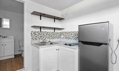 Kitchenette inside a HOME9 studio with stainless refrigerator, stovetop, and open shelving